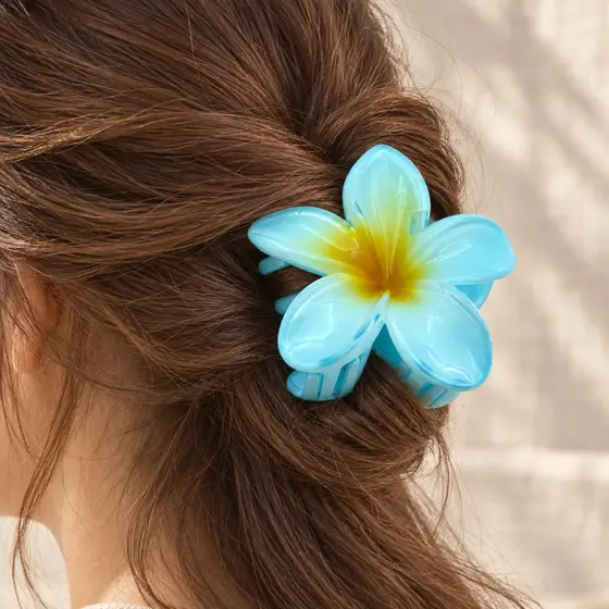 Blue frangipani hair claw · Yellow center · Worn hair claw detail